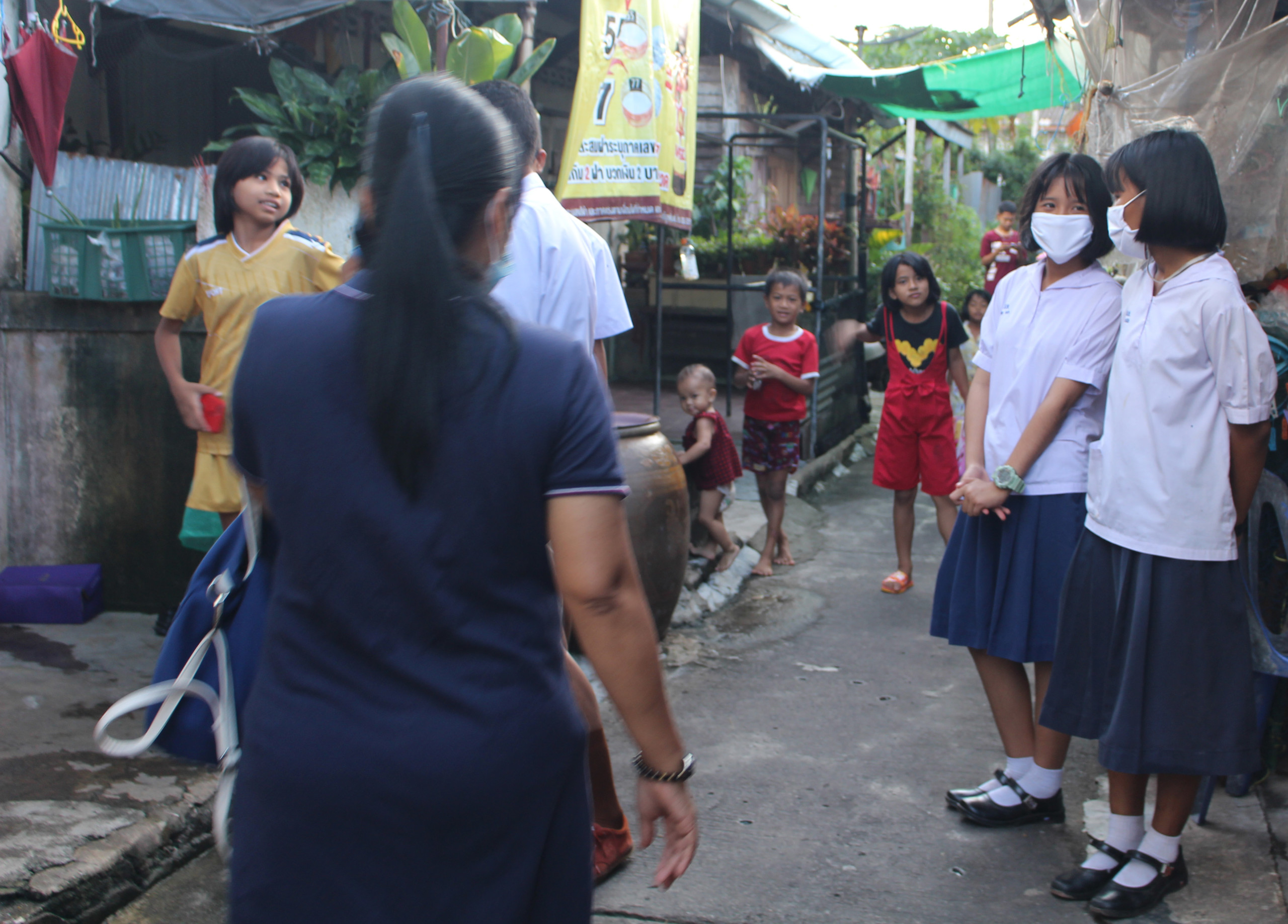 Two young gaenam still in their school uniforms chat in the migrant community. (Photo: Partners Asia)
